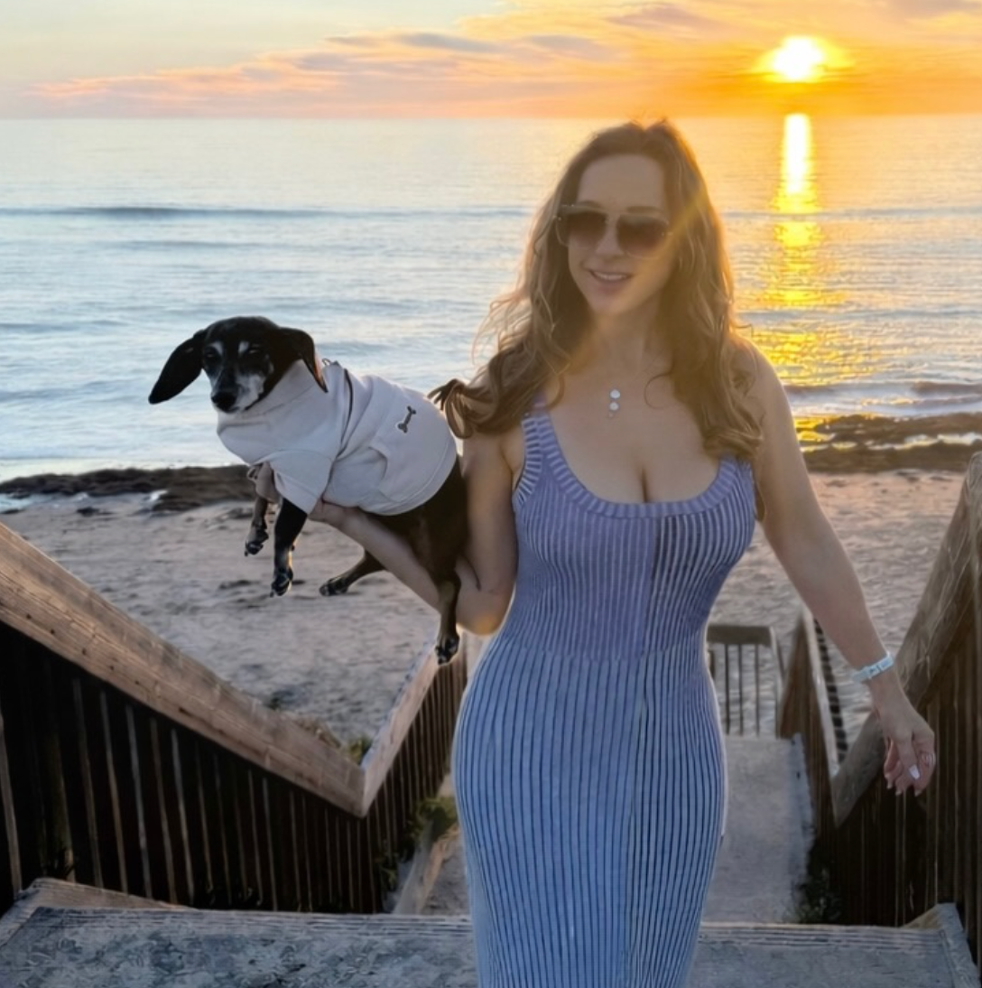 jessica ann holding her pup Karma by the ocean at sunset